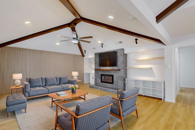 living area with light wood-style floors, visible vents, a fireplace, and lofted ceiling with beams