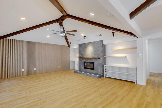 unfurnished living room featuring visible vents, a tiled fireplace, lofted ceiling with beams, ceiling fan, and wood finished floors