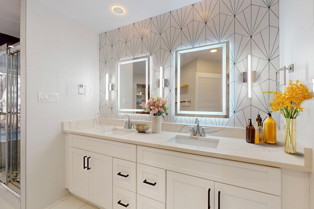 bathroom featuring double vanity, a stall shower, tile walls, and a sink