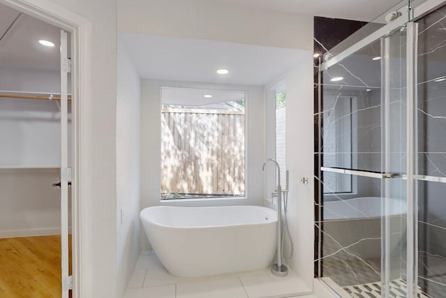 full bath featuring recessed lighting, a freestanding bath, a spacious closet, a shower stall, and tile patterned floors