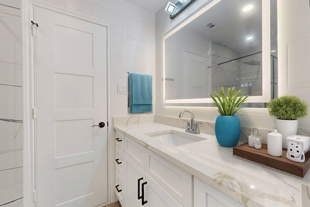 bathroom with visible vents, walk in shower, and vanity