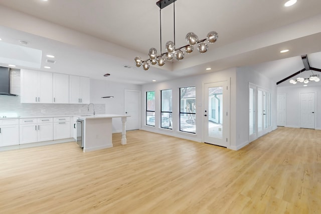 kitchen with tasteful backsplash, open floor plan, a peninsula, light wood-style floors, and a sink