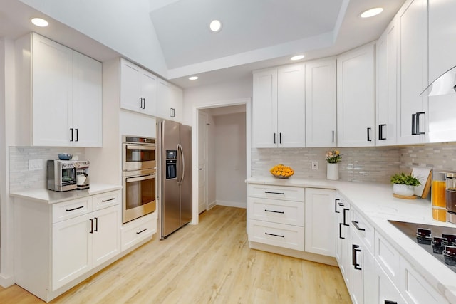 kitchen with light wood finished floors, stainless steel appliances, recessed lighting, lofted ceiling, and white cabinetry