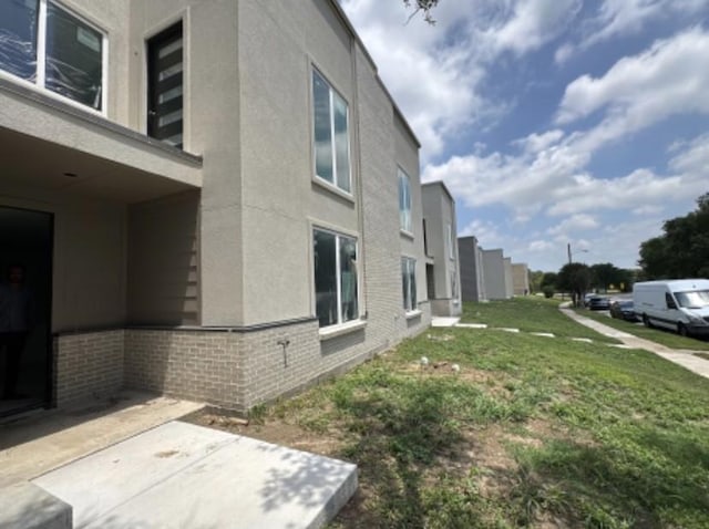 9475 Timberleaf Dr, Dallas, TX 75243 - view of home's exterior featuring stucco siding, brick siding, a patio area, and a lawn
