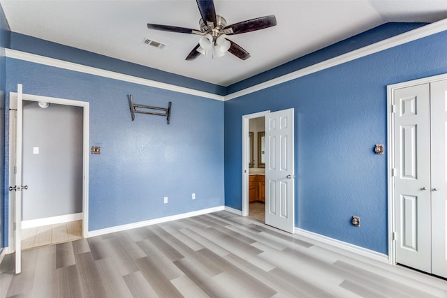 unfurnished bedroom featuring baseboards, visible vents, wood finished floors, and ensuite bathroom