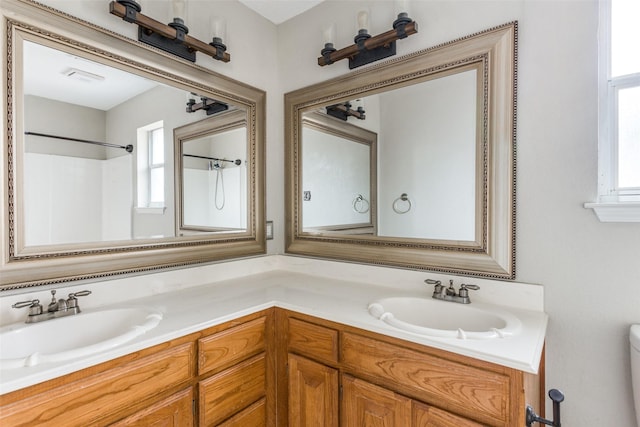 full bathroom with toilet, double vanity, and a sink