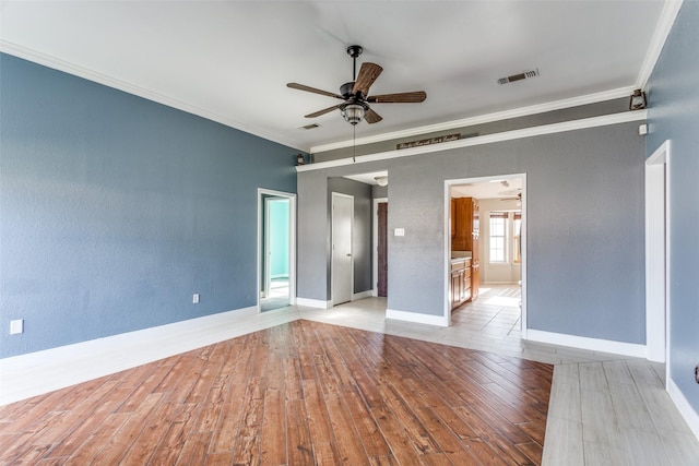 empty room with ceiling fan, wood finished floors, visible vents, and crown molding