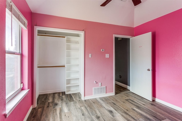 unfurnished bedroom with multiple windows, wood finished floors, visible vents, and baseboards