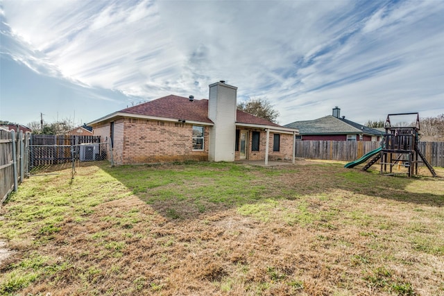 back of house featuring a playground, a yard, brick siding, and a patio area