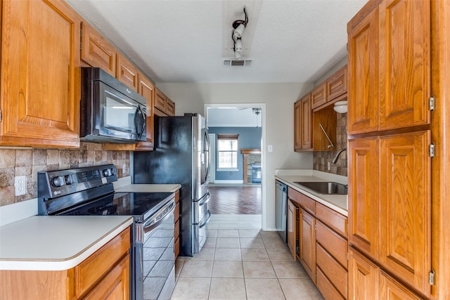 kitchen featuring light countertops, light tile patterned flooring, a sink, black microwave, and stainless steel electric range