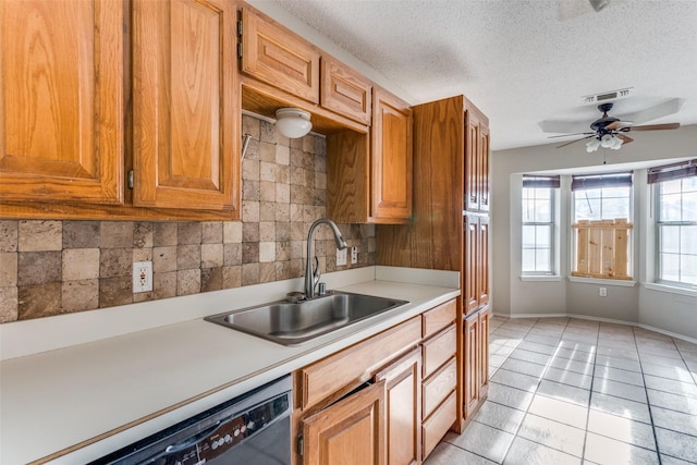 kitchen with visible vents, dishwasher, a sink, light countertops, and backsplash