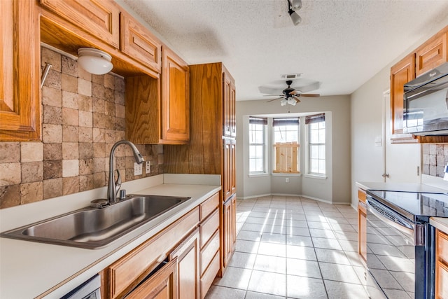 kitchen with light countertops, electric range, backsplash, a sink, and black microwave