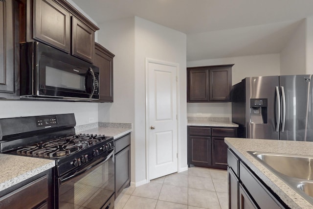 kitchen with light countertops, light tile patterned flooring, a sink, dark brown cabinets, and black appliances