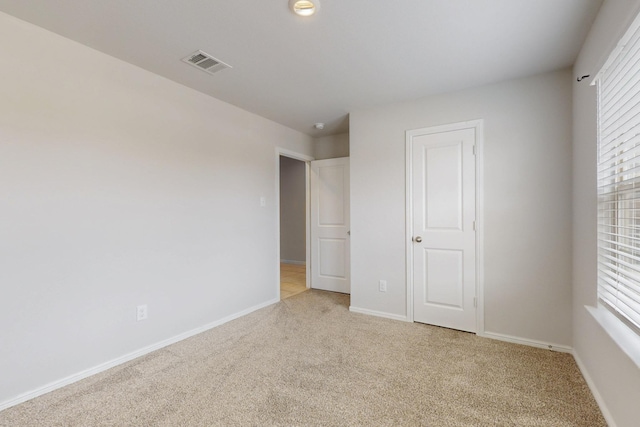 unfurnished bedroom featuring light carpet, visible vents, and baseboards