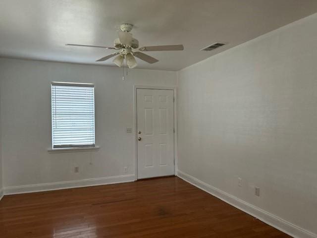 spare room with a ceiling fan, visible vents, baseboards, and wood finished floors