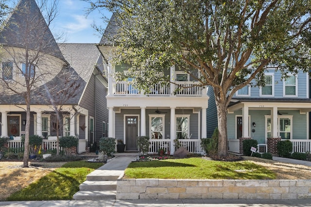 view of front of property featuring covered porch, a front lawn, and a balcony