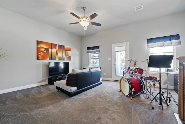 living area featuring carpet floors, visible vents, baseboards, and a ceiling fan