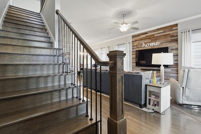 staircase with visible vents, ceiling fan, wood finished floors, crown molding, and wood walls