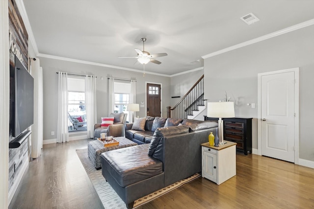 living room with baseboards, visible vents, ornamental molding, wood finished floors, and stairs