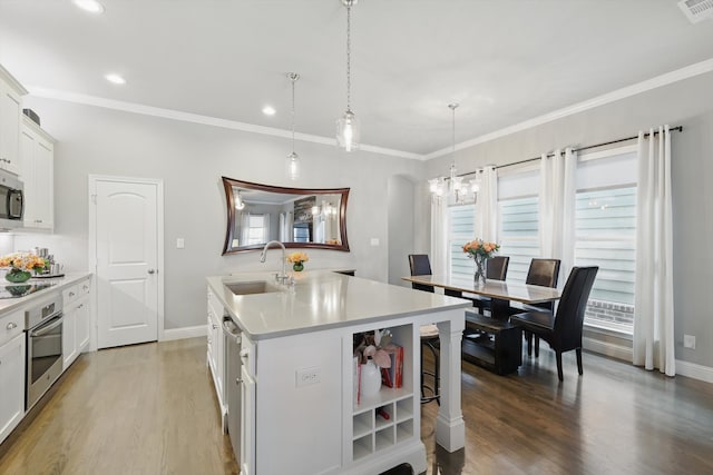 kitchen featuring stainless steel appliances, light wood-type flooring, light countertops, and a sink