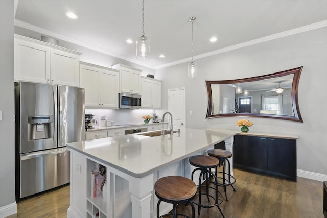 kitchen featuring a breakfast bar area, stainless steel appliances, a sink, dark wood-style floors, and an island with sink