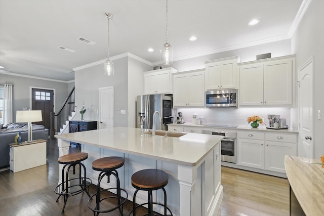 kitchen featuring tasteful backsplash, visible vents, appliances with stainless steel finishes, light wood-type flooring, and a sink