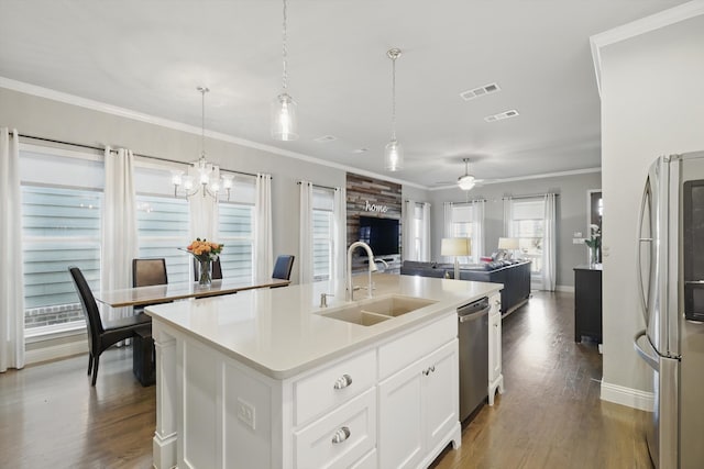 kitchen with visible vents, appliances with stainless steel finishes, open floor plan, crown molding, and a sink