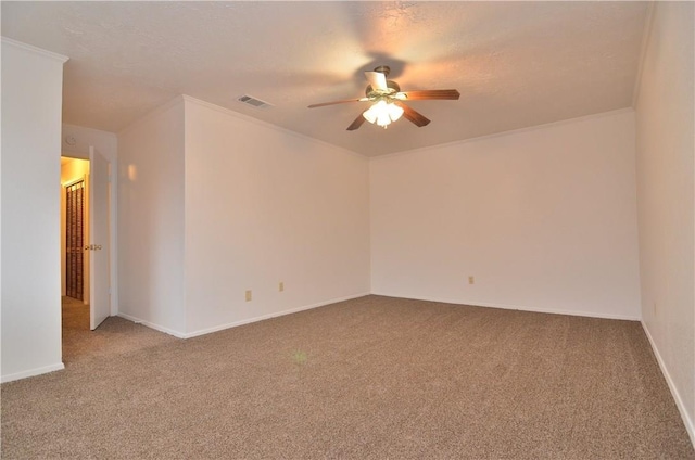 carpeted empty room featuring baseboards, visible vents, a ceiling fan, and ornamental molding