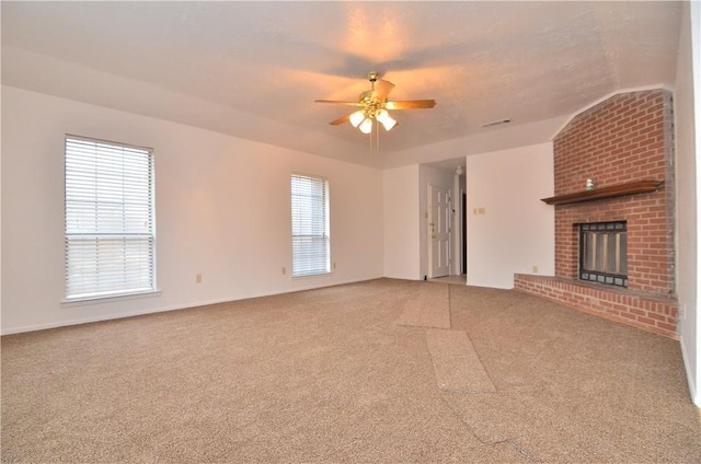 unfurnished living room with ceiling fan, a fireplace, and light colored carpet