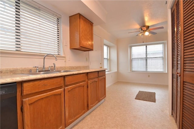 kitchen with light countertops, a ceiling fan, brown cabinetry, a sink, and dishwasher