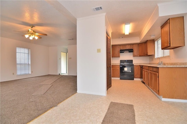 kitchen with under cabinet range hood, light carpet, stove, visible vents, and light countertops