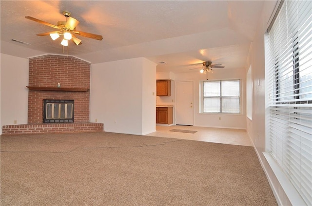 unfurnished living room with visible vents, a ceiling fan, light colored carpet, lofted ceiling, and a brick fireplace