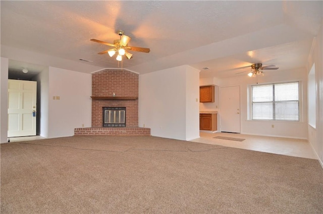 unfurnished living room with light colored carpet, lofted ceiling, ceiling fan, a textured ceiling, and a brick fireplace