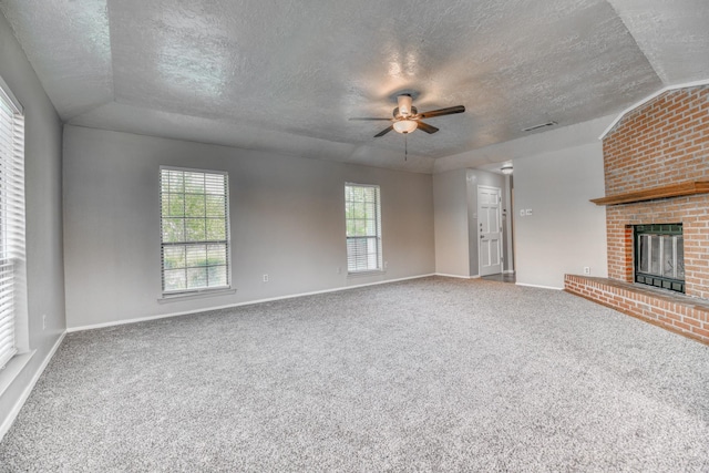 unfurnished living room featuring a textured ceiling, a brick fireplace, ceiling fan, and carpet floors