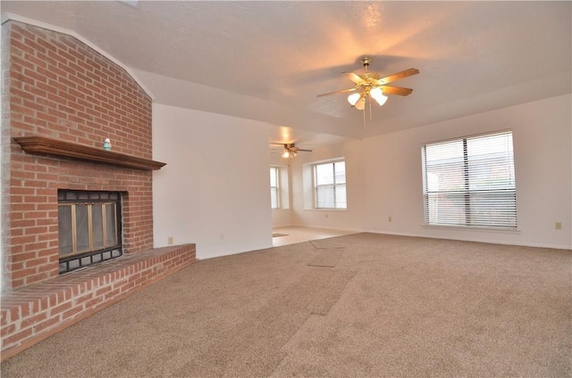 unfurnished living room with vaulted ceiling, carpet, a fireplace, and ceiling fan