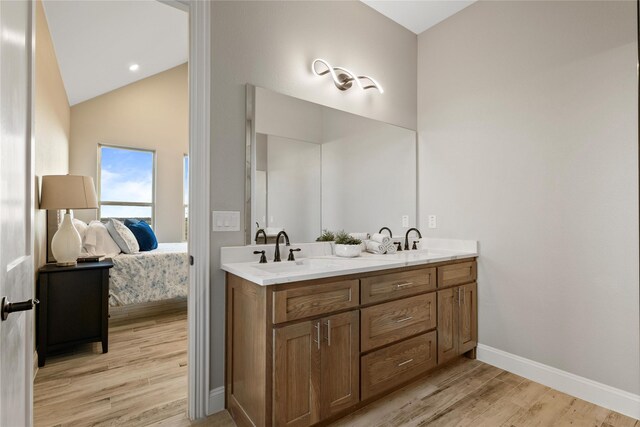 ensuite bathroom featuring ensuite bathroom, lofted ceiling, wood finished floors, a sink, and double vanity