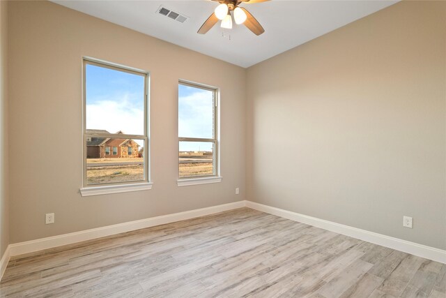 spare room featuring light wood-type flooring, baseboards, visible vents, and a ceiling fan