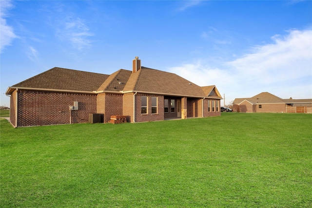 rear view of property featuring a yard, brick siding, and central air condition unit