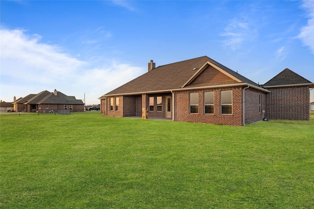 back of property with brick siding, a lawn, and a chimney