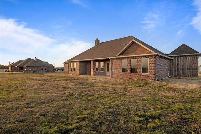 rear view of house featuring brick siding, a yard, and a chimney