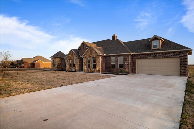 view of front of property with brick siding, roof with shingles, concrete driveway, a front yard, and a garage