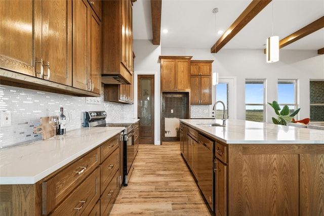 kitchen featuring brown cabinets, beamed ceiling, stainless steel appliances, a large island with sink, and a sink