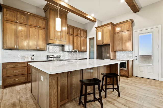 kitchen with electric range, light wood-style flooring, brown cabinets, a sink, and beam ceiling