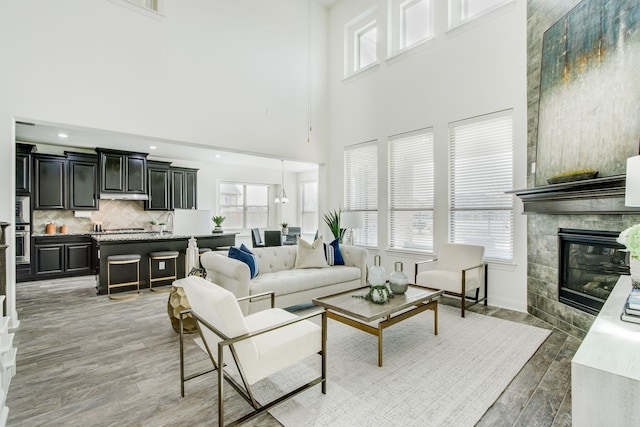 living area with a tile fireplace, light wood finished floors, and recessed lighting