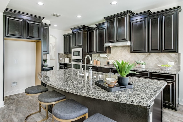 kitchen with stainless steel appliances, dark cabinetry, a sink, and visible vents