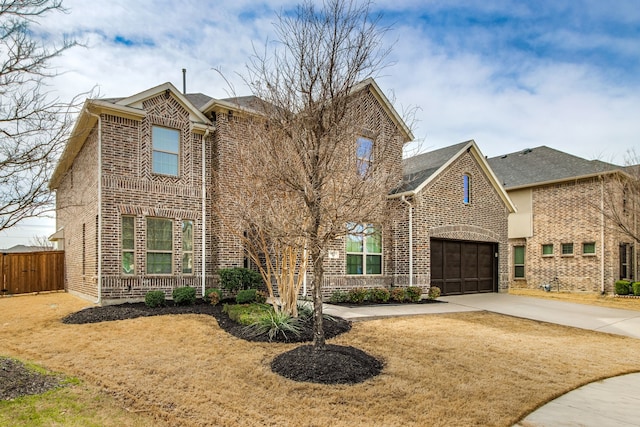 traditional-style home featuring a garage, fence, concrete driveway, and brick siding