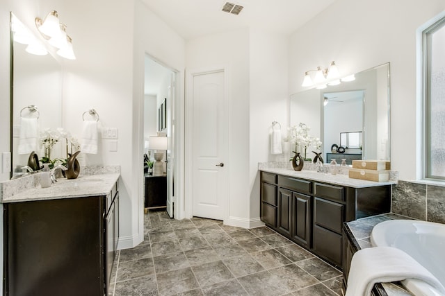 bathroom with a sink, a bathtub, visible vents, and two vanities