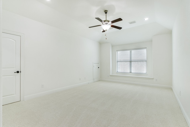 empty room featuring light carpet, lofted ceiling, visible vents, and baseboards