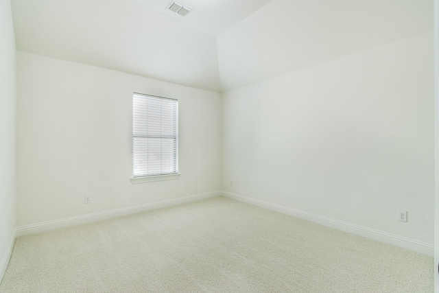 empty room featuring lofted ceiling, baseboards, visible vents, and light colored carpet