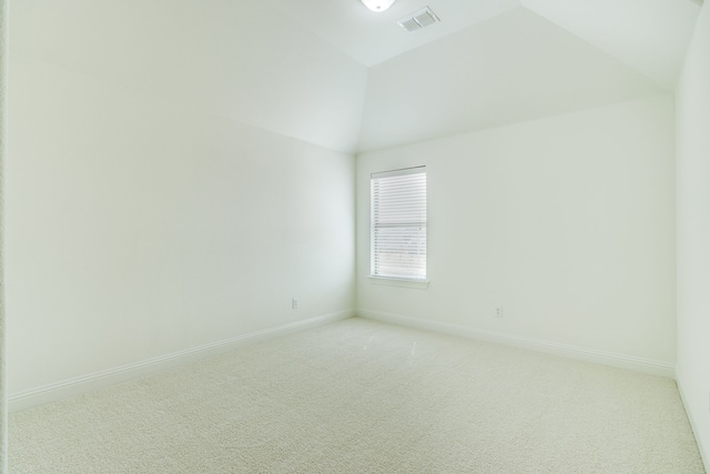 spare room featuring lofted ceiling, baseboards, visible vents, and light colored carpet